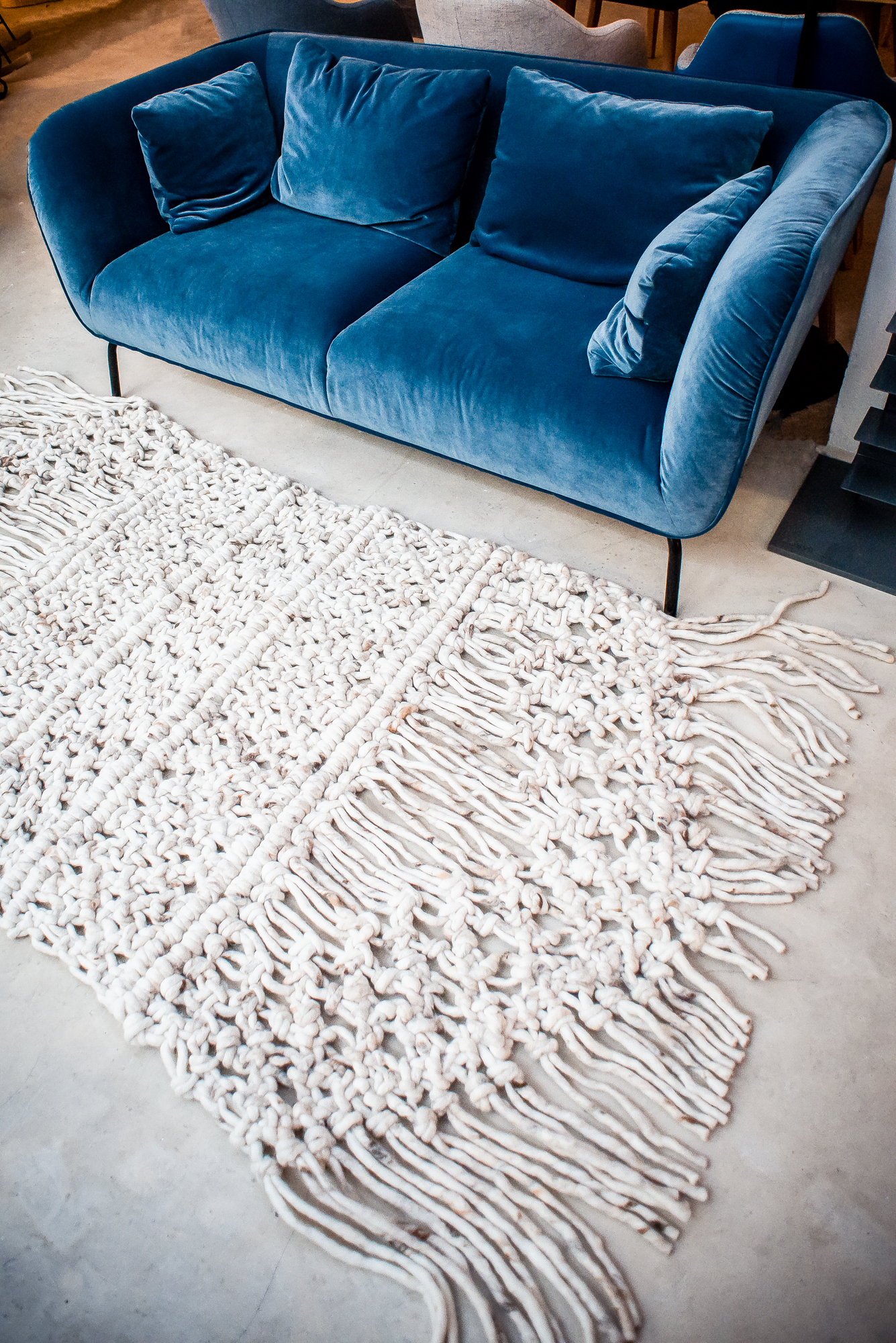 Blue velvet sofa and woven wool rug in modern Scandinavian-style living room.