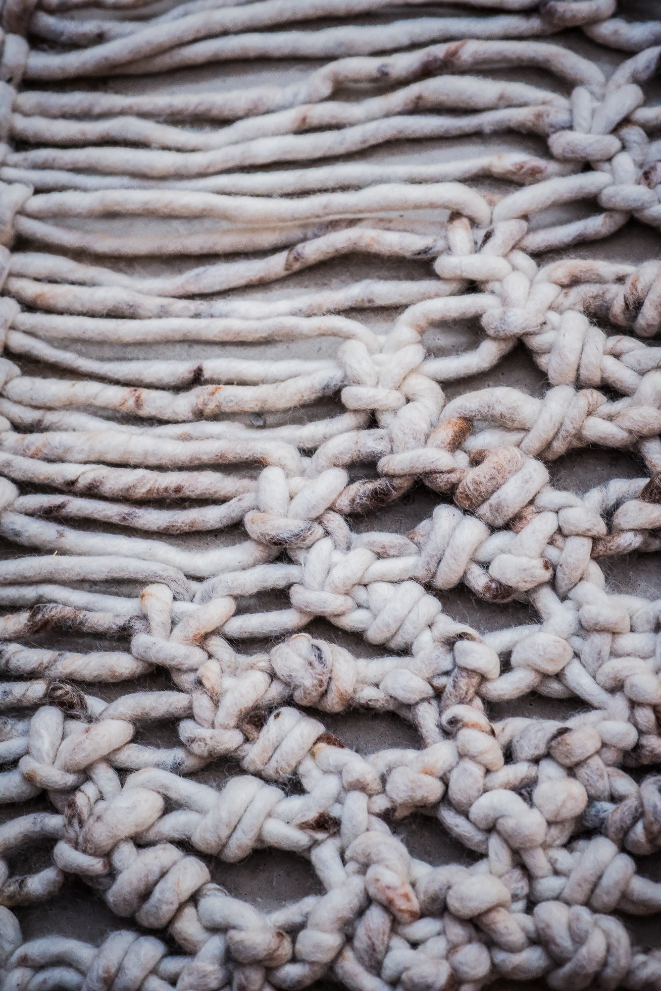 Handmade wool rug with braided texture and tassel edging photographed from above.
